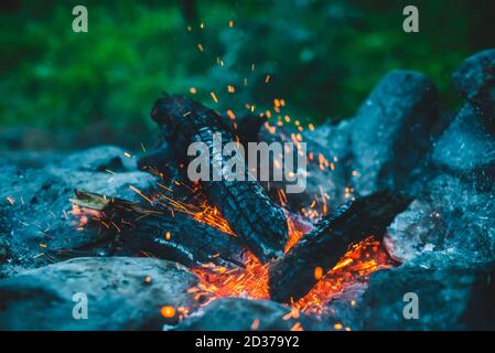 Vividi boschi di fuoco bruciati in closeup fuoco. Sfondo atmosferico con fiamma arancione di fuoco. Immagine full frame di falò con scintille in bok Foto Stock