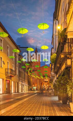 Ombrelli verdi appesi lungo la strada principale di Monza durante il tramonto, Lombardia, Italia Foto Stock