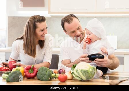 Felici genitori seduti in cucina e si prepara a cucinare con la loro baby cuoco. Foto Stock