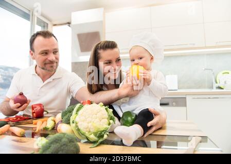 Felici genitori seduti in cucina e si prepara a cucinare con la loro baby cuoco. Foto Stock