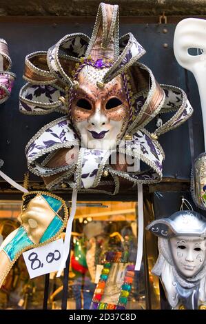 Maschere colorate per il Carnevale Veneziano appese in vendita in un negozio di souvenir di strada a Venezia Foto Stock