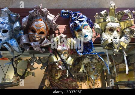 Maschere colorate per il Carnevale Veneziano appese in vendita in un negozio di souvenir di strada a Venezia Foto Stock