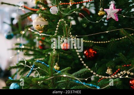 Primo piano di decorazioni per alberi di Natale, ghirlande e perline sui rami di un albero di Natale. Foto Stock