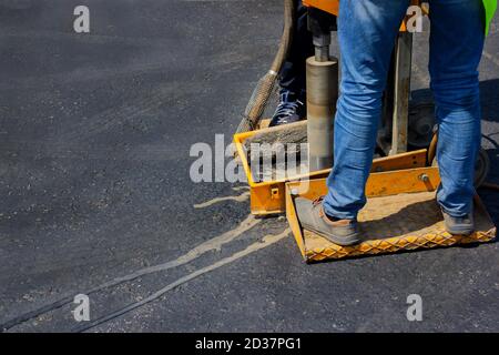 Il costruttore con macchina troncatrice sta perforando nuovo asfalto per controllarlo. Foto Stock