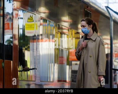 Mosca. Russia. 4 ottobre 2020 UNA giovane donna che indossa una maschera medica protettiva si trova sulla piattaforma di una stazione della metropolitana, in attesa di salire a bordo del treno Foto Stock