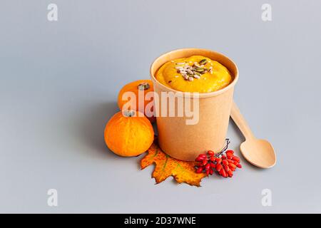Zuppa di crema di zucca vegana spessa con semi in una tazza di carta da artigianato usa e getta. Zuppa da andare, consegna di cibo sano. Togliere il cibo. Foto Stock