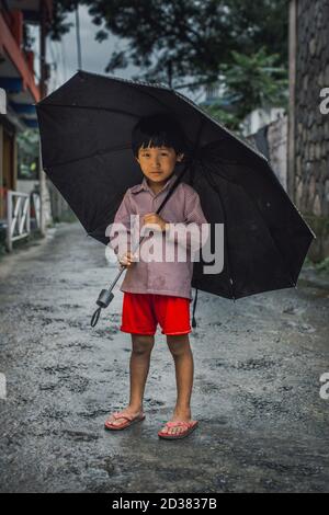 Divisa Dalit che gioca con il loro ombrello a Pokhara. Foto Stock
