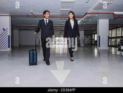 Una coppia d'affari cammina attraverso il moderno parcheggio di Bangkok Foto Stock