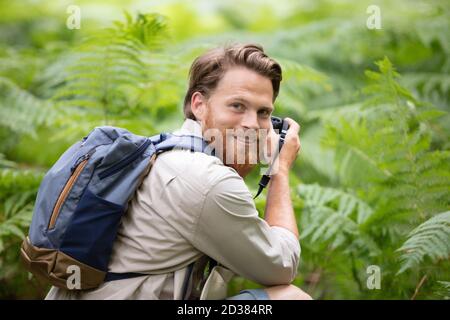 escursionista maschile guardando attraverso binocoli nella foresta Foto Stock