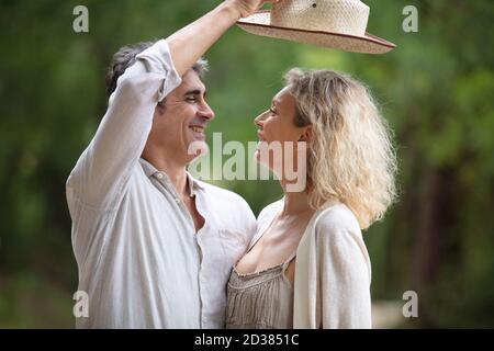 uomo anziano che mette un cappello di sole sulla sua testa di wifes Foto Stock