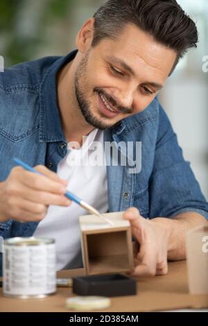 uomo che dipinge una piccola scatola di legno Foto Stock