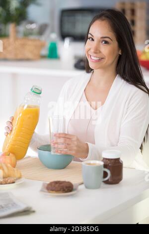 bella donna che beve succo d'arancia al mattino Foto Stock