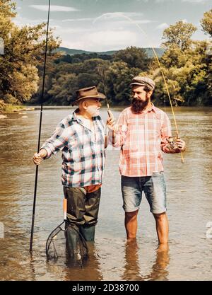 Pescatore pesca in un fiume con una canna da pesca. Felice nonno e nipote con canne da pesca sul fiume ormeggio. Pesca a mosca nell'incontaminato Foto Stock