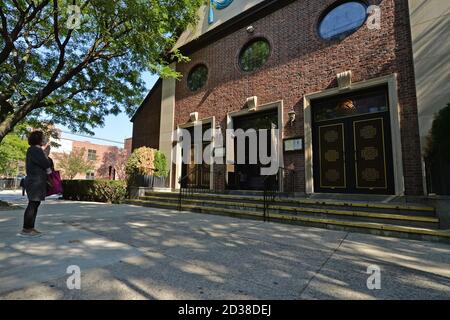 Una donna si ferma a pregare di fronte alla Chiesa cattolica di nostra Signora dell'Angelus nella zona rossa designata di Rego Park, Queens, NY, 7 ottobre 2020. Gov. Andrew Cuomo ha adottato un sistema di zone colorate a tre livelli (giallo, arancione e rosso), piuttosto che utilizzare i codici di avviamento postale, per identificare i quartieri che stanno vedendo un picco significativo nelle infezioni da Coronavirus, e imporre diverse restrizioni in base al colore della zona, il rosso essendo il più alto. Le restrizioni della zona rossa includono un massimo di 10 persone all'interno delle case di culto, sono vietate le riunioni di gruppo, solo le imprese essenziali possono rimanere aperte, Foto Stock