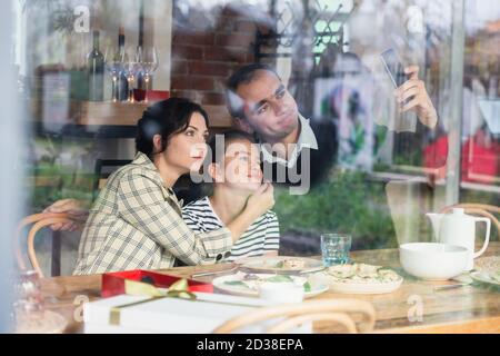 Una famiglia felice di tre selfie in un caffè. Foto Stock