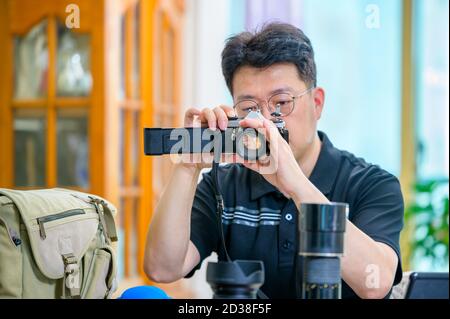 Un uomo asiatico di mezza età il cui hobby è una fotocamera reflex a pellicola da 35mm/135mm. Foto Stock