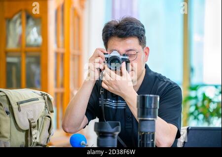 Un uomo asiatico di mezza età il cui hobby è una fotocamera reflex a pellicola da 35mm/135mm. Foto Stock