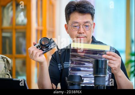 Un uomo asiatico di mezza età il cui hobby è una fotocamera reflex a pellicola da 35mm/135mm. Foto Stock