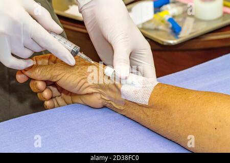 Siringa a pressione del medico nel tappo eparina mano del paziente Foto Stock