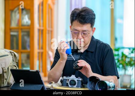 Un uomo asiatico di mezza età il cui hobby è una fotocamera reflex a pellicola da 35mm/135mm. Foto Stock