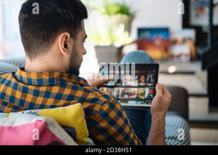 Uomo che sceglie il filmato per lo streaming sul Tablet computer Foto Stock