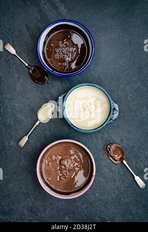 Tre tipi di cioccolato fuso in ciotole. Cioccolato fondente, cioccolato al latte, cioccolato bianco Foto Stock