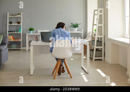 Donna di affari che lavora duro scrivere nel notebook e usando il computer seduto alla scrivania in ufficio a casa Foto Stock