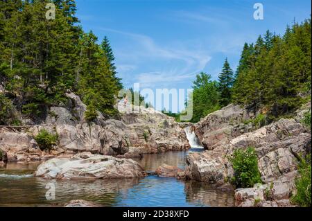 Coppia escursionistica riposante su una scogliera sopra Broad River. Cascate e piscine lungo il torrente. Moosehorn Trail, Fundy National Park, New Brunswick, Canada Foto Stock