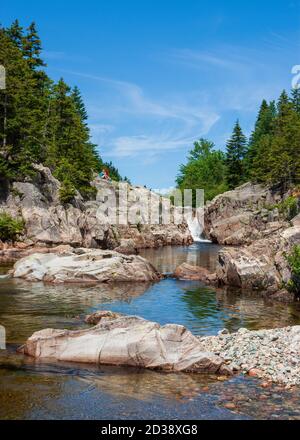 Coppia escursionistica riposante su una scogliera sopra Broad River. Cascate e piscine lungo il torrente. Moosehorn Trail, Fundy National Park, New Brunswick, Canada Foto Stock