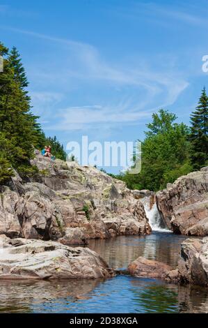 Coppia escursionistica riposante su una scogliera sopra Broad River. Cascate e piscine lungo il torrente. Moosehorn Trail, Fundy National Park, New Brunswick, Canada Foto Stock