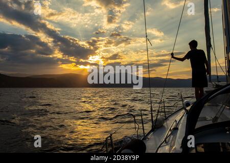 Un ragazzo su una barca a vela che viaggia nel golfo Saronico, Grecia Foto Stock