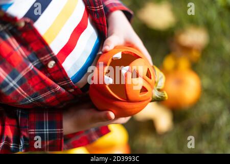 Mano del capretto che tiene la lampada della zucca di Jack'o, trucco o trucco il giorno di Halloween. Concetto per le vacanze autunnali background. Foto Stock