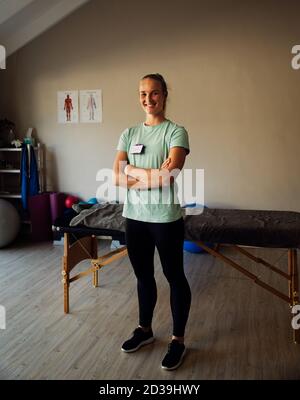 Ritratto a corpo pieno di sano intern in piedi in sala esercizi waitng per il suo primo paziente ferito. Foto Stock