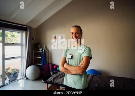 Ritratto di fisioterapista caucasica femminile in pratica a casa, sorridente e felice Foto Stock