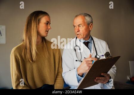 anziano medico maschile dà consulenza medica a giovani donne Foto Stock