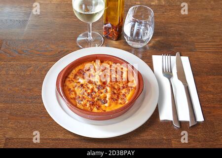 Argenteria su tavolo di legno marrone e gratin bianco di maccheroni in ciotola di ceramica. Foto Stock
