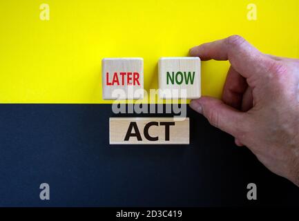 Agisci ora o più tardi. L'uomo d'affari tiene un cubetto con la parola 'ora'. Cubetti di legno con le parole 'ACT, Later'. Splendido sfondo giallo e nero. Spazio di copia. Foto Stock