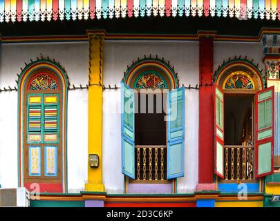Colorate persiane in legno su un edificio storico restaurato in Little India, Singapore. Foto Stock