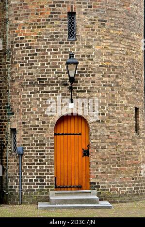 Porta in pannelli di legno in una torretta medievale cilindrica in mattoni. Foto Stock