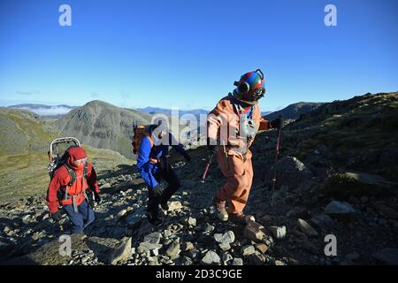 Il veterano Lloyd Scott, che sta tentando di scalare le tre vette in aiuto della beneficenza Lord's Taverners mentre indossa una tuta per immersioni in alto mare, durante la sua sfida a Scafell Pike, nel Lake District National Park, in Cumbria. Foto Stock