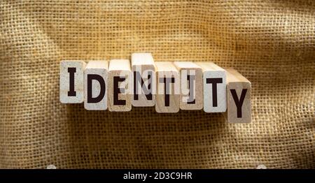 Blocchi di legno formano le parole 'identità' su uno sfondo di tela bella. Concetto aziendale. Spazio di copia. Foto Stock