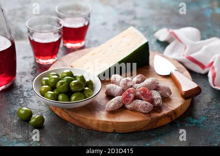 Piatto antipasto. Fuet mini salsicce, olive verdi e formaggio su tagliere di legno, fuoco selettivo Foto Stock