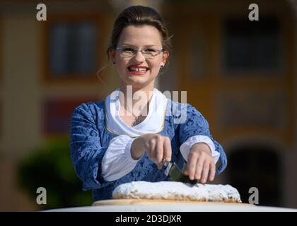 Dresda, Germania. 8 ottobre 2020. Johanna Meitzner, la 26a Dresden Stollen Girl, taglia il primo Stollen di Natale durante la sua esibizione nel Pillnitz Palace Park. L'apprendista fornaio di 21 anni è l'ambasciatore dello Stollen di Natale di Dresda per la durata di un anno per conto dei panifici Stollen di Dresda. Credit: Robert Michael/dpa-Zentralbild/dpa/Alamy Live News Foto Stock