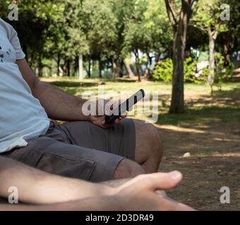 Mano dell'uomo che usa lo smartphone nel parco naturale all'aperto Foto Stock