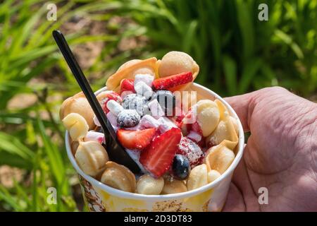 gelato al waffle con mirtilli e fragole nel mano Foto Stock