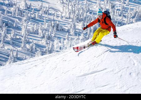 Sciatore in discesa sugli sci in alta montagna contro il cielo blu Foto Stock