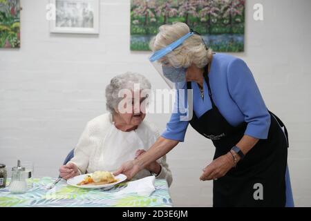 La Duchessa di Cornovaglia, nel suo ruolo di presidente, Royal Voluntary Service, indossa uno scudo facciale mentre serve un pranzo durante una visita al Royal Voluntary Service Mill End Lunch Club di Rickmansworth, Hertfordshire, incontrare i volontari che hanno superato le recenti sfide poste dalla pandemia per ripristinare le tanto necessarie sessioni di pranzo. Foto Stock