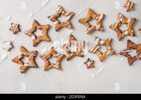 In casa stella di Natale forma lo zucchero caramellato i biscotti con la glassa bianca su sfondo marmo. Laici piana, copia dello spazio. Dolce di Natale o Capodanno dono. Foto Stock