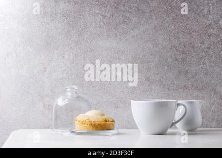 Dolce pera tartlet con tazza di caffè espresso e la brocca di crema piedi su marmo bianco tavola con muro grigio a sfondo. Stile minimalista. Copia sp Foto Stock