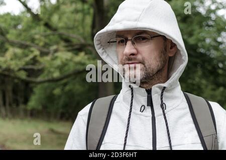 Ritratto di un uomo di mezza età in un maglione con cappuccio in un parco Foto Stock